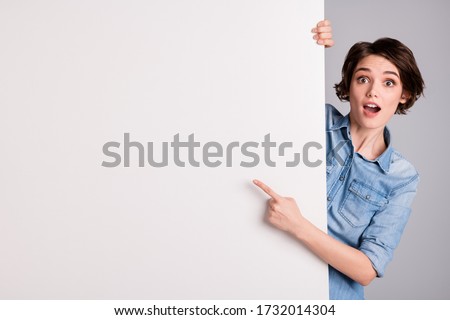 Photo of funny pretty cheerful lady holding hands paper direct finger side white empty space poster proposing buy advert place wear casual denim shirt isolated grey color background Royalty-Free Stock Photo #1732014304