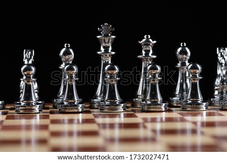 Silvery chess figures standing on wooden chessboard. Intellectual and tactical game. Strategy planning, leadership and teamwork business concept. Close-up steel chess pieces in row on black background