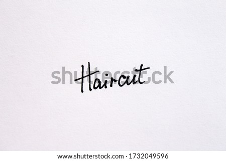 Close-up of a word Haircut handwritten message on a white background.