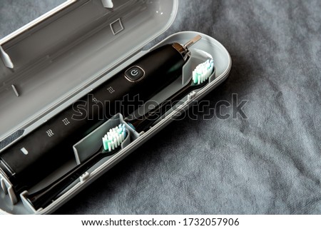 Modern black sonic or electric toothbrush in travel case on background with copy space. Concept of professional oral care and healthy teeth by using sonic smart toothbrush. Minimal design