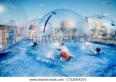 Children playing inside of floating water walking balls