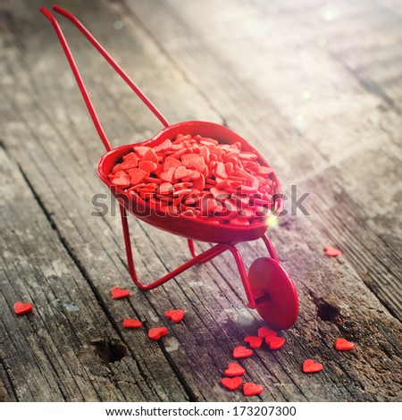 Red Wheelbarrow and Tiny Hearts, on Wooden Background