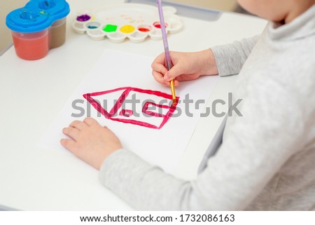 Girl is painting her dream house on a large white paper. Children's creativity.