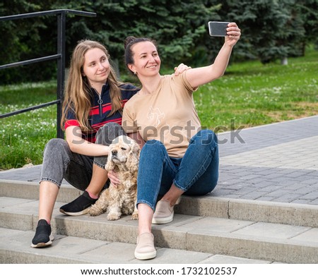 Family, leisure and technology concept. Smiling happy mother and daughter taking selfie together in the park
