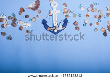 Decorative anchor on seashells and water drops background. Sea. Seashells on blue background.  Anchor thermometer. Abstract sea mood picture.  