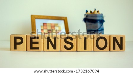 Wooden cubes with the inscription 'pension'. Frame with a picture and a bag with pencils in the background. Beautiful white background, copy space.