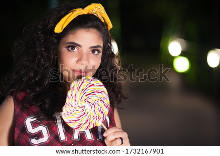 Beautiful brazilian  teenager holding a giant lollipop. she is looking at the camera.