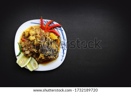 Fish head curry, locally called "Murighanta" a traditional food of  India and Bangladesh. Garnished with red chilies and lemons. 
