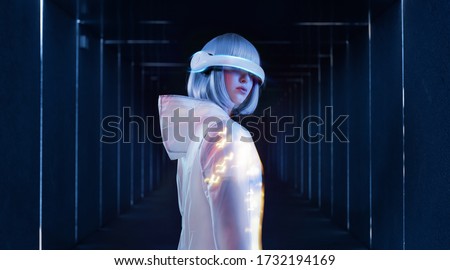 Beautiful woman with blue hair in futuristic costume over dark background. Girl in glasses of virtual reality. Augmented reality game, future technology, AI concept. VR. Neon light.