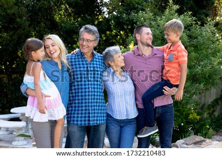 Three generation Caucasian family spending time in their garden on a sunny day, smiling, embracing and interacting.