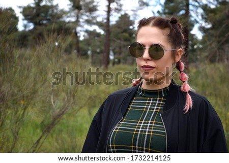 Woman with sunglasses in the field in spring, with her hair up