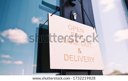 The wooden sign with text: Open for take-out and delivery hangin