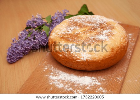Fresh white bread. Homebaked bread. On a wooden background. A branch of lilac. Aroma in the kitchen

