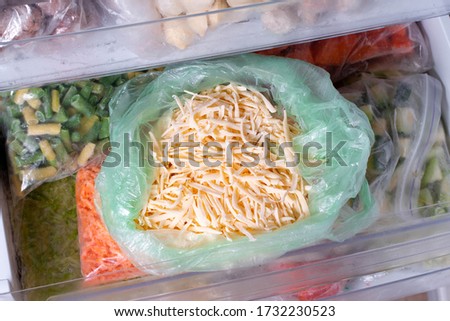 Frozen grated cheese. Frozen food in the freezer