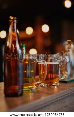 Picture of beer glasses and bottles on bar counter. Bar interior.