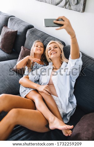 Mom and daughter take a selfie on vacation and smile at the camera in the summer