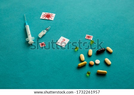 Different colorful pills, red question mark, medical syringe, vaccine ampoule and covid-19 icons on a blue background. Concept of health and medical care. Low angle view, close-up.