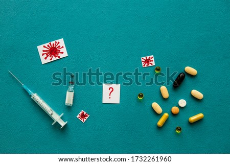 Different colorful pills, red question mark, medical syringe, vaccine ampoule and covid-19 icons on a blue background. Concept of health and medical care. Flat lay, top view, copy space.