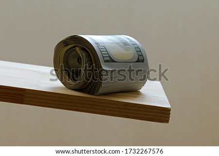 bundle of dollars rolls onto the edge of a wooden board Royalty-Free Stock Photo #1732267576