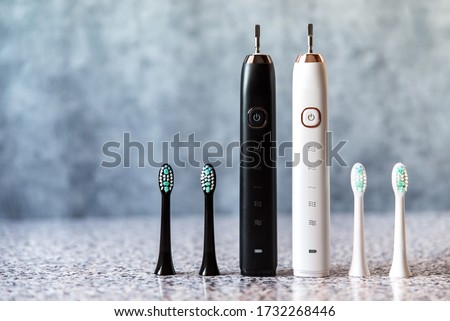 Modern black and white sonic or electric toothbrush set with replacement heads. Concept of professional oral care and healthy teeth by using sonic smart toothbrush. Minimal design