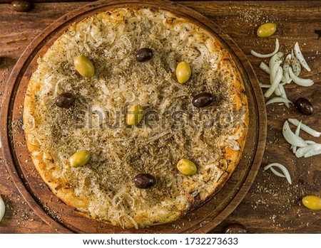 Handmade Delicious onion Pizza  and melted cheese with green and black olives on top on a  rustic wood table - Top View - Selective Focus -Baking and comfort concept.
