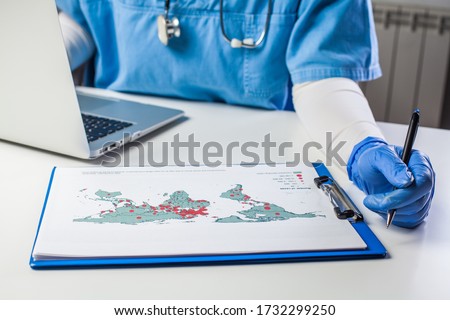 Medical worker analyzing COVID-19 world map,Coronavirus global pandemic outbreak crisis,stats showing worldwide number of infected patients,death toll and mortality rate,possible infection new wave Royalty-Free Stock Photo #1732299250