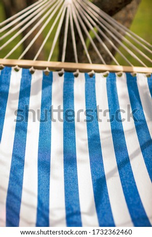 Summer vibes, outdoor fun and calm pleasure, treat on hammock. White and blue stripes.