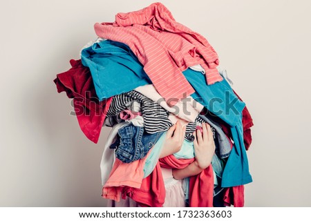 Mommy little helper. Cute Caucasian girl sorting clothes. Adorable funny child arranging organazing clothing. Kid holding messy stack pile of clothes things. Home chores housework. Royalty-Free Stock Photo #1732363603