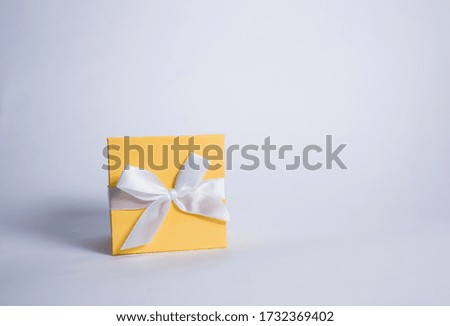 Closed yellow gift box with white ribbon on a white background with space for text. Sale.