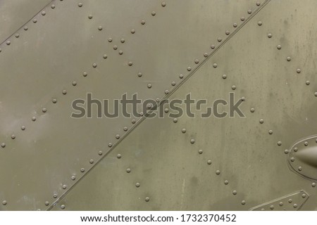 Old silver metal surface of the aircraft fuselage with rivets. Iron plate,steel sheet texture,pattern and background. Aluminum surface of the aircraft fuselage. Smooth rows of rivets. Royalty-Free Stock Photo #1732370452