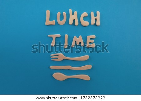 Lunch time text composed with wooden artistic letters with wooden fork, knife and spoon design over blue background