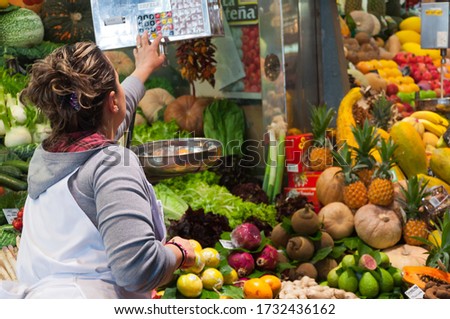 A woman calculating the weight of the vegetables and fruits in the market