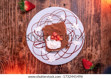 An overhead shot of a chocolate biscuit with whipped cream and strawberry