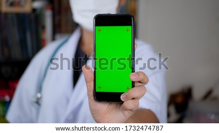Doctor hand holding smartphone green screen display