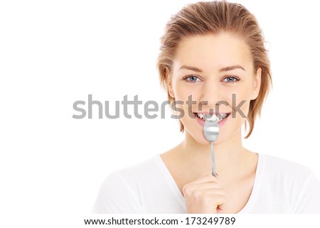 A picture of a young woman posing with a teaspoon over white background