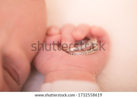 Baby hand. Newborn hand holding wedding rings. Family and love concept. Royalty-Free Stock Photo #1732558619