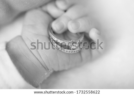 Baby hand. Newborn hand holding wedding rings. Family and love concept. Royalty-Free Stock Photo #1732558622