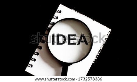 Opened old blank book with magnifying glass with text Idea