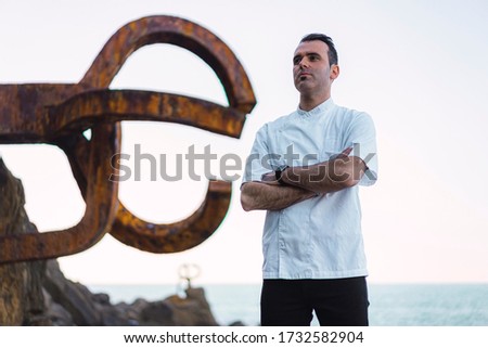 A cook in a white apron pictured on the coast