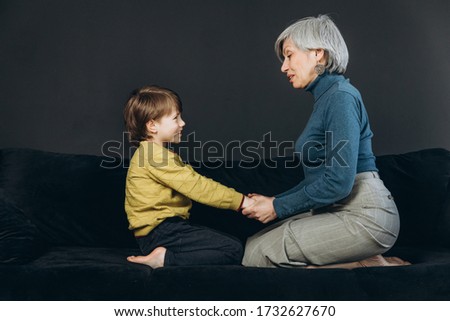 A little boy and his grandmother are having fun together against a dark background