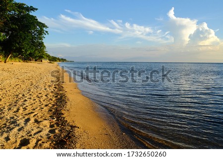 Seascape with sandy beach, calm sea and cloud formation looking like volcano eruption