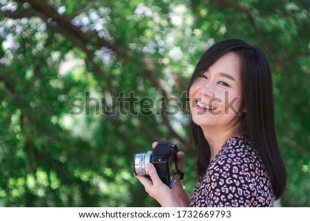 Portrait of beautiful smiling asian woman with holding camera at summer green park.