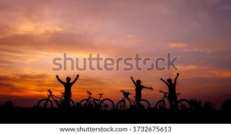 Family cyclist and Bicycle silhouettes on the dark background of sunsets
