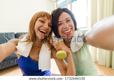 Happy mother and daughter taking a selfie workout gym at home during quarantine. Concept about people, family, gym at home, sport.