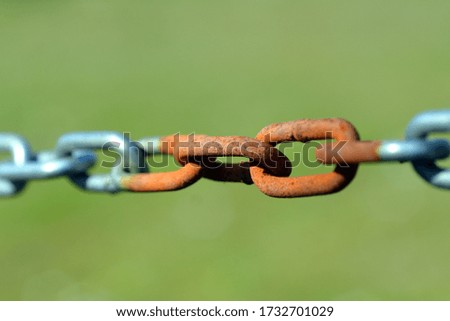 Macro photo of a rusty  chain on a green outdoor background as symbol for connection as well as segregation