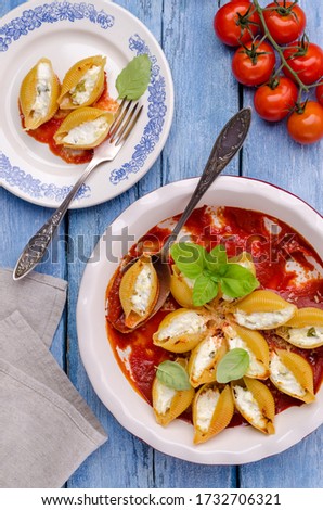 Pasta stuffed with ricotta and spinach in tomato sauce in a ceramic dish on a wooden background. Selective focus.