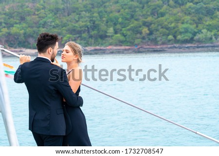 luxury relaxing couple traveler in nice dress and suite stand and hug in love at part of cruise yacht with background of sea and white sky. Concept business travel.