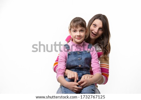 A girl sits on her mothers lap and stares in surprise at the frame