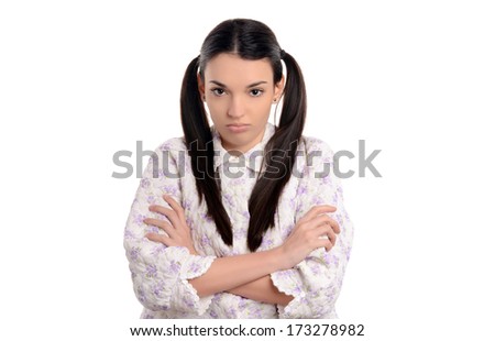 Grumpy in the morning. Beautiful young woman in pajamas upset standing with her hands crossed. Girl with two ponytails. Isolated on white.