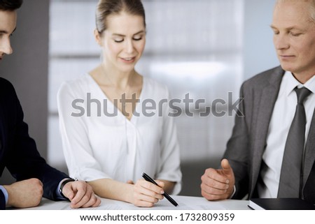 Elderly businessman and group of business people discussing contract in office. Woman and lawyers working together at meeting. Teamwork and cooperation
